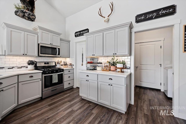 kitchen with decorative backsplash, appliances with stainless steel finishes, high vaulted ceiling, gray cabinets, and dark hardwood / wood-style floors