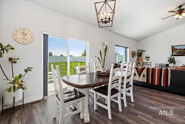 dining area featuring ceiling fan with notable chandelier, dark hardwood / wood-style flooring, and lofted ceiling