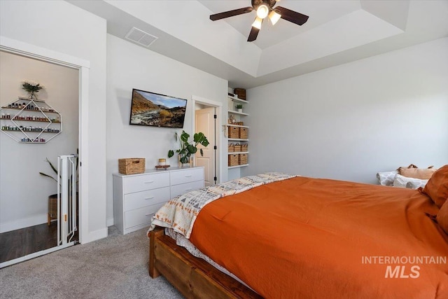 bedroom with a tray ceiling, ceiling fan, and light carpet