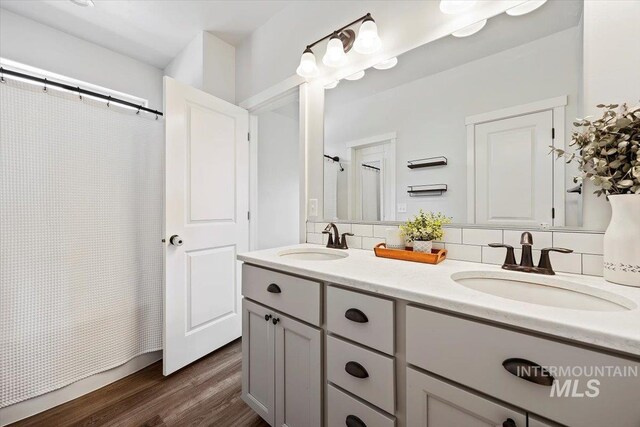 1418 N Birch St, Jerome, ID 83301 - full bath featuring double vanity, wood finished floors, a shower with shower curtain, and decorative backsplash
