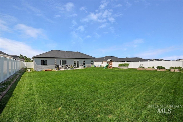 back of house featuring a playground and a yard