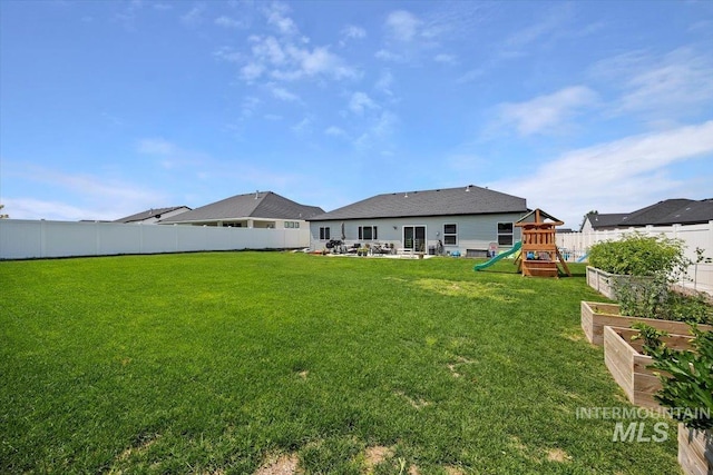 rear view of house with a playground and a yard