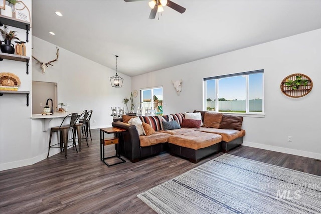 living room featuring lofted ceiling, ceiling fan with notable chandelier, a healthy amount of sunlight, and dark hardwood / wood-style floors