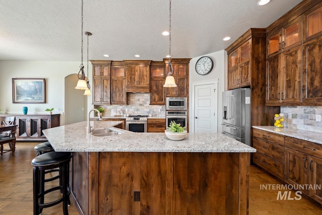 12225 W Indus Dr, Star, ID 83669 - kitchen with stainless steel appliances, a sink, arched walkways, a spacious island, and decorative backsplash