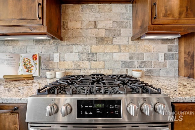 12225 W Indus Dr, Star, ID 83669 - kitchen with brown cabinetry, stainless steel range with gas cooktop, decorative backsplash, and light stone countertops