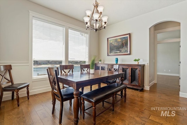 12225 W Indus Dr, Star, ID 83669 - dining room featuring arched walkways, wood finished floors, a wealth of natural light, and an inviting chandelier