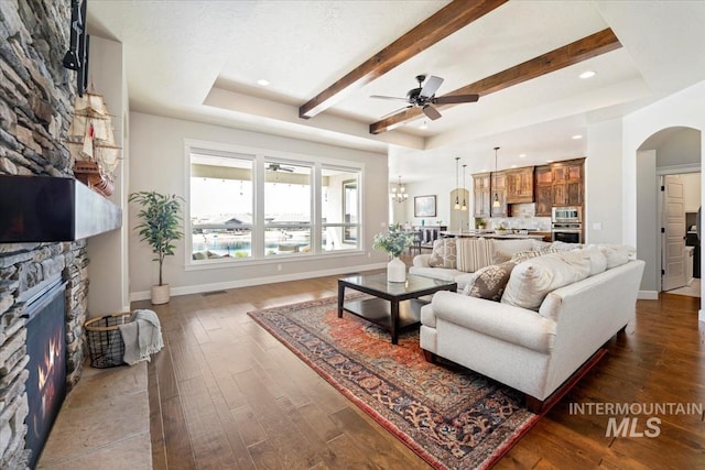 12225 W Indus Dr, Star, ID 83669 - living area with a ceiling fan, arched walkways, a tray ceiling, a fireplace, and dark wood finished floors
