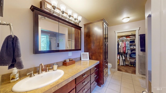 bathroom featuring tile patterned flooring, a spacious closet, toilet, and vanity