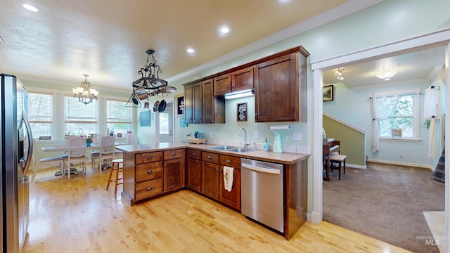 kitchen with a sink, light countertops, an inviting chandelier, ornamental molding, and stainless steel appliances