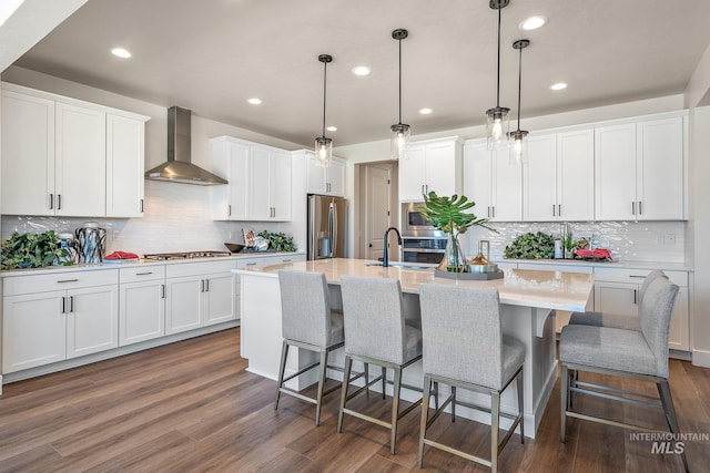 1210 Stirling Meadows Ct, Middleton, ID 83644 - kitchen with appliances with stainless steel finishes, wall chimney range hood, a center island with sink, white cabinetry, and recessed lighting