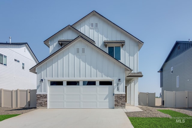 modern farmhouse featuring board and batten siding, a gate, a garage, and concrete driveway