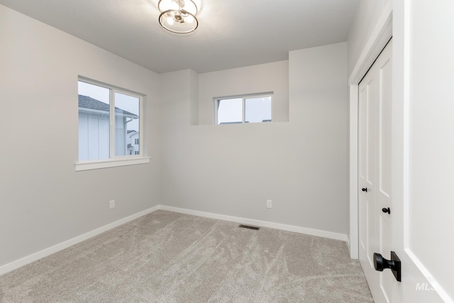 unfurnished bedroom with a closet, carpet flooring, visible vents, and baseboards