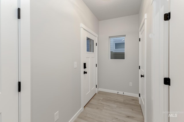 doorway to outside with light wood-style flooring and baseboards