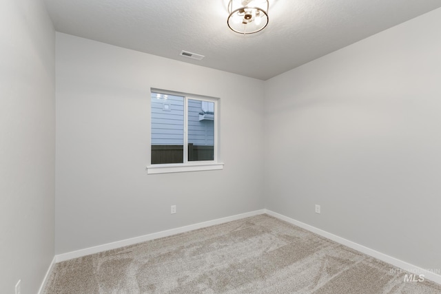 carpeted empty room featuring visible vents, a textured ceiling, and baseboards