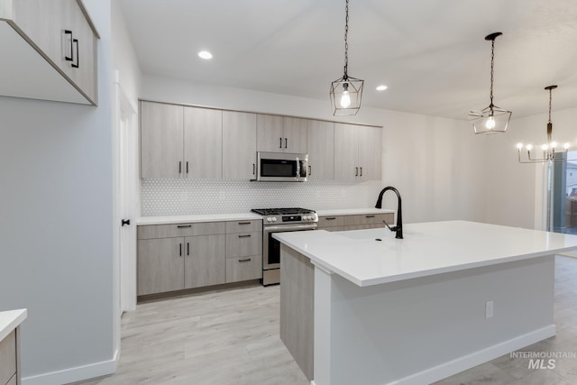 kitchen with stainless steel appliances, a sink, light countertops, decorative backsplash, and modern cabinets