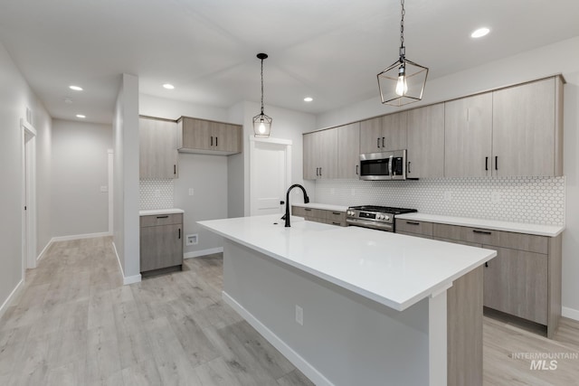 kitchen featuring appliances with stainless steel finishes, light countertops, light wood-style flooring, and modern cabinets