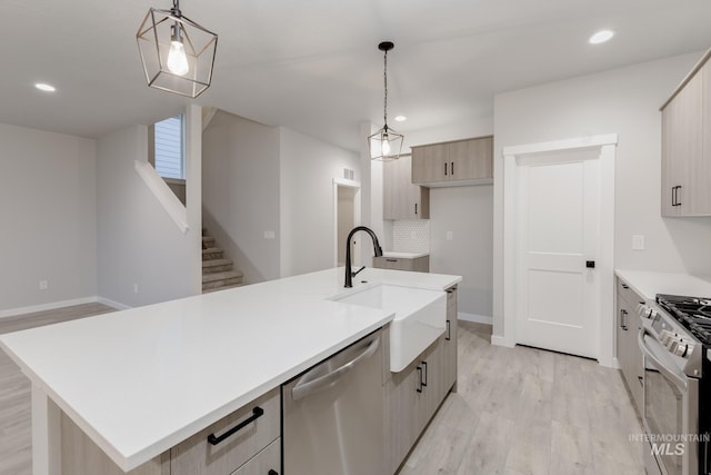 kitchen with recessed lighting, a sink, light countertops, appliances with stainless steel finishes, and light wood-type flooring