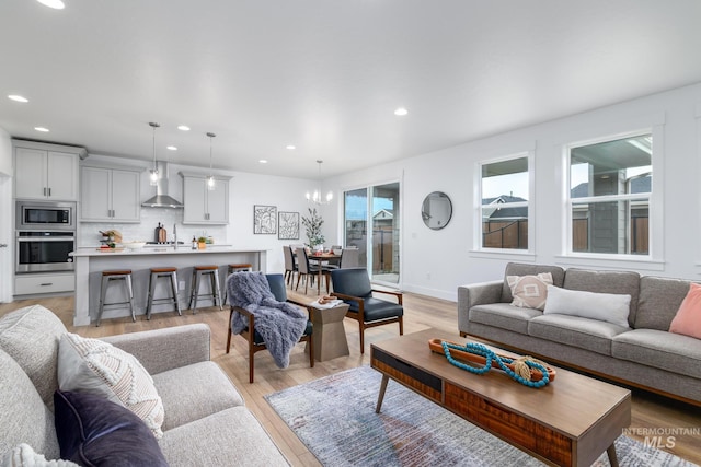 living room featuring a notable chandelier, light wood-type flooring, and sink