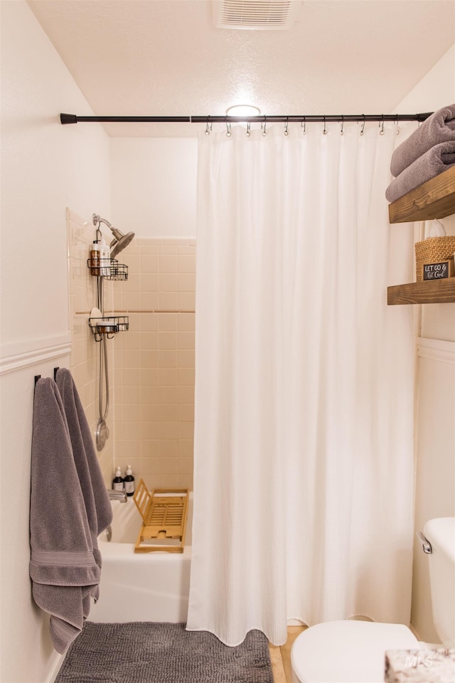 bathroom with toilet and a shower with shower curtain