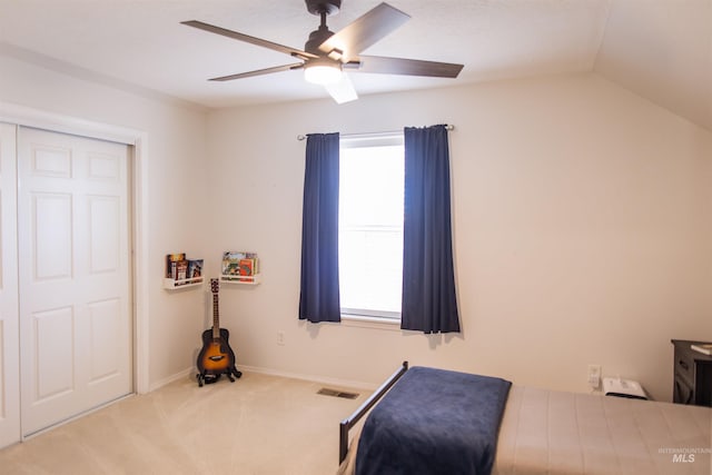 bedroom with a closet, light colored carpet, vaulted ceiling, and ceiling fan