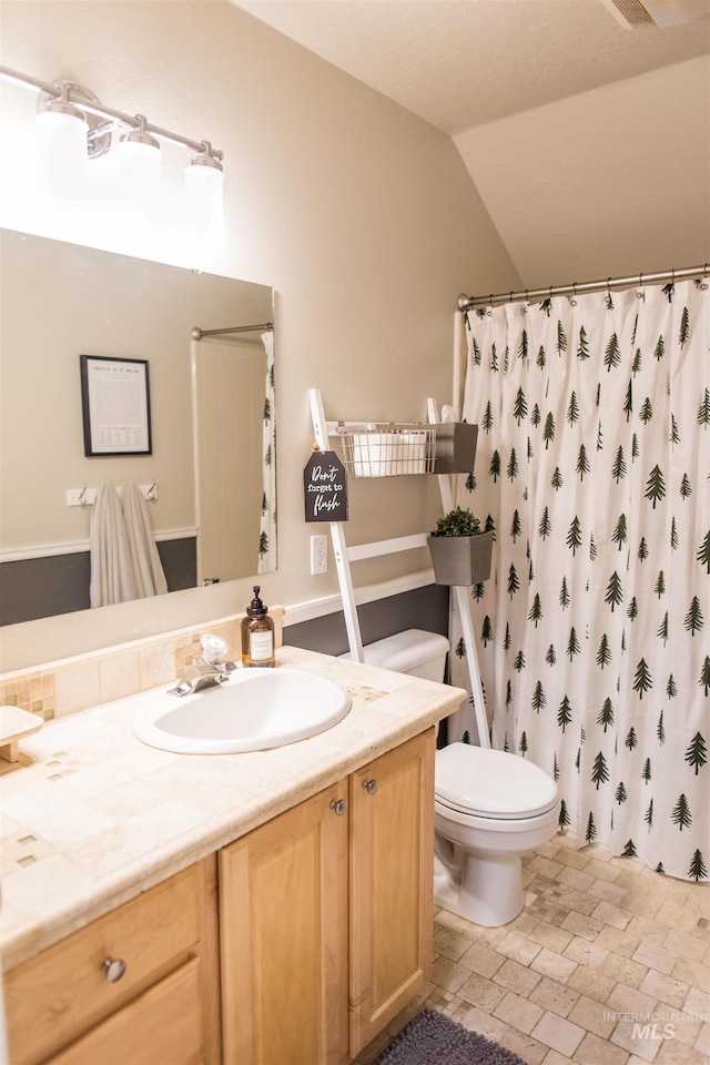 bathroom with a shower with curtain, vanity, toilet, and lofted ceiling