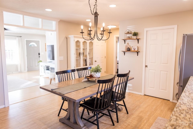 dining area with light hardwood / wood-style flooring and an inviting chandelier