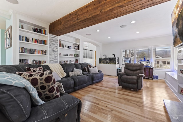 living room featuring built in features, arched walkways, recessed lighting, ornamental molding, and light wood-type flooring