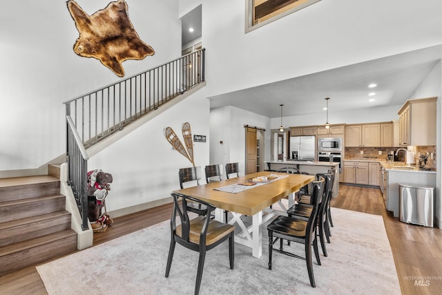 1089 Graham Dr, Mccall, ID 83638 - dining space featuring light wood-style floors, stairway, a towering ceiling, a barn door, and recessed lighting