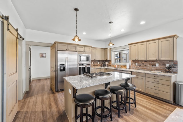 1089 Graham Dr, Mccall, ID 83638 - kitchen featuring appliances with stainless steel finishes, a barn door, light wood-style floors, decorative backsplash, and recessed lighting