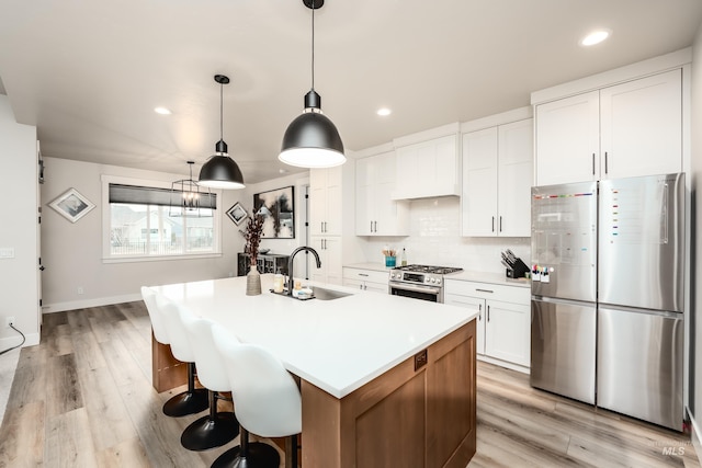 kitchen featuring backsplash, premium range hood, appliances with stainless steel finishes, white cabinetry, and a sink