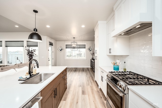 kitchen featuring gas range, premium range hood, light countertops, and a sink