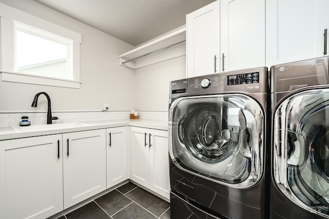 clothes washing area with a sink, dark tile patterned flooring, cabinet space, and washer and clothes dryer