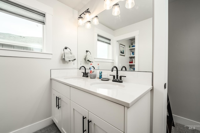 full bath featuring double vanity, baseboards, and a sink