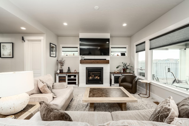 living room featuring recessed lighting, baseboards, and a large fireplace