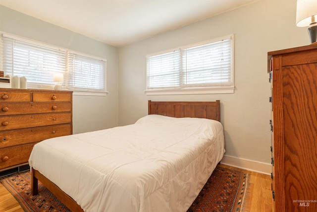 bedroom featuring multiple windows, wood finished floors, and baseboards