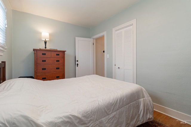 bedroom featuring wood finished floors, baseboards, and a closet