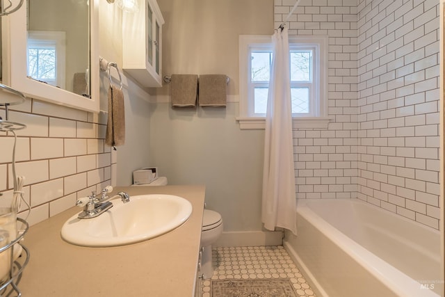 full bathroom with vanity, baseboards, shower / bath combo with shower curtain, toilet, and tasteful backsplash