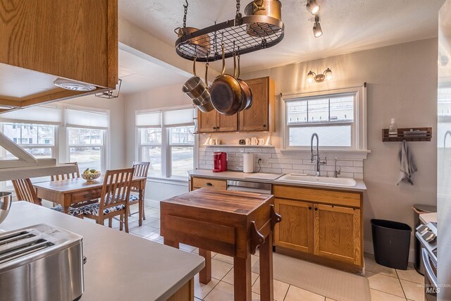 kitchen with a sink, brown cabinets, tasteful backsplash, and light tile patterned floors