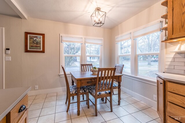 dining area featuring a notable chandelier, baseboards, and light tile patterned floors