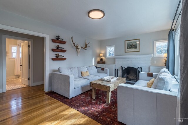 living area with a brick fireplace and wood finished floors
