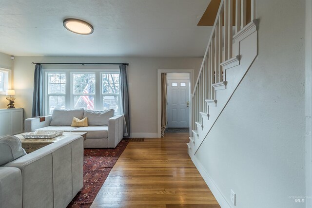 living area with stairs, wood finished floors, and baseboards