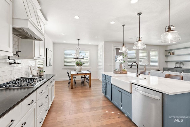 kitchen with a wealth of natural light, appliances with stainless steel finishes, blue cabinetry, and premium range hood