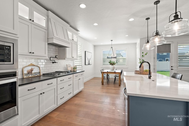 kitchen featuring decorative light fixtures, a center island with sink, appliances with stainless steel finishes, and plenty of natural light