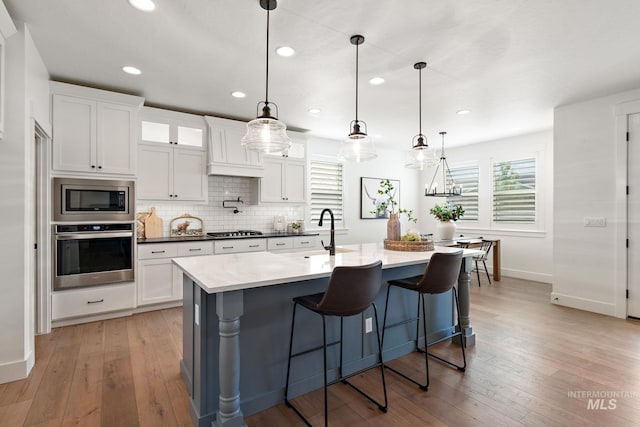 kitchen featuring pendant lighting, stainless steel appliances, sink, and white cabinetry