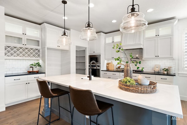 kitchen with pendant lighting, a large island, hardwood / wood-style flooring, and tasteful backsplash