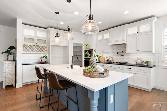 kitchen with decorative light fixtures, light wood-type flooring, and white cabinetry