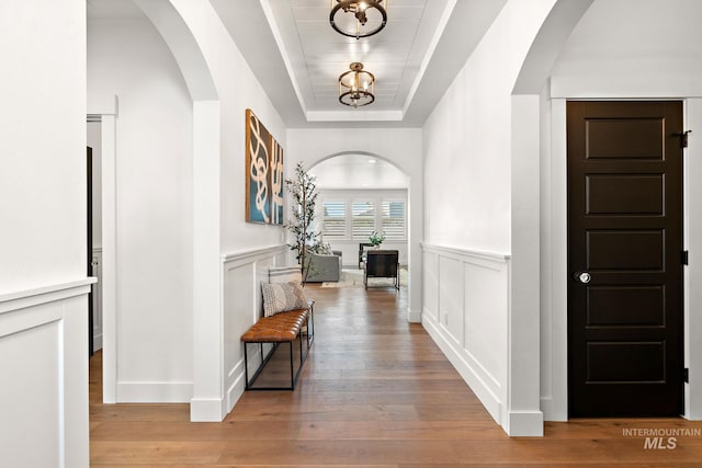 entrance foyer with light wood-type flooring, a tray ceiling, and a notable chandelier