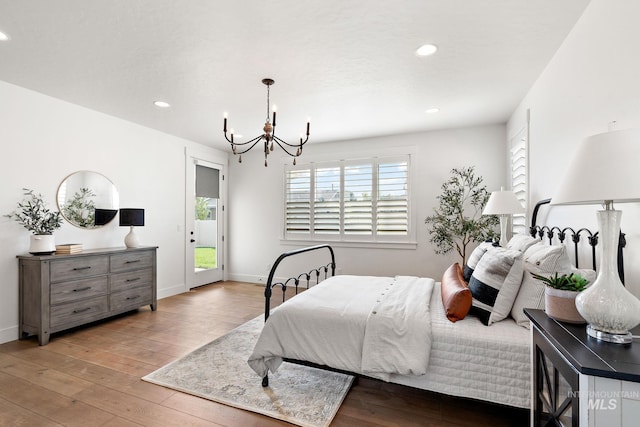 bedroom with access to outside, an inviting chandelier, and light hardwood / wood-style flooring