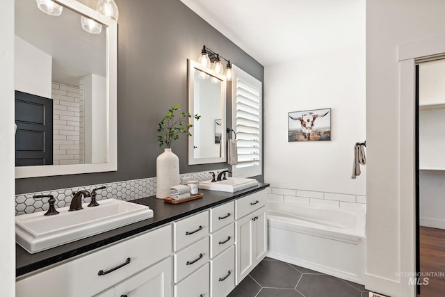 bathroom with a tub to relax in, tasteful backsplash, vanity, and tile patterned floors