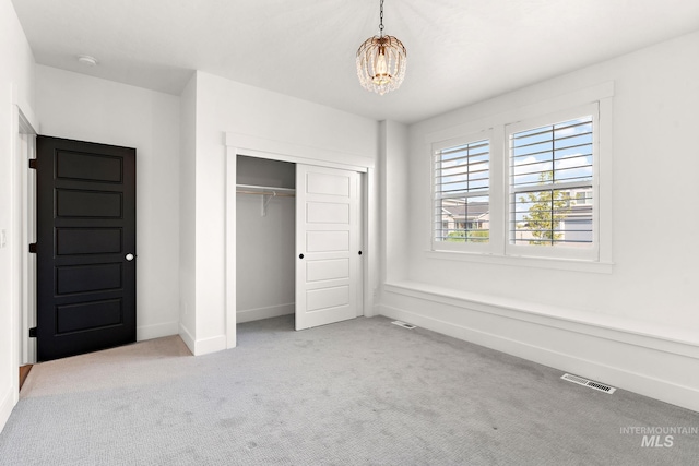 unfurnished bedroom featuring light carpet, a notable chandelier, and a closet